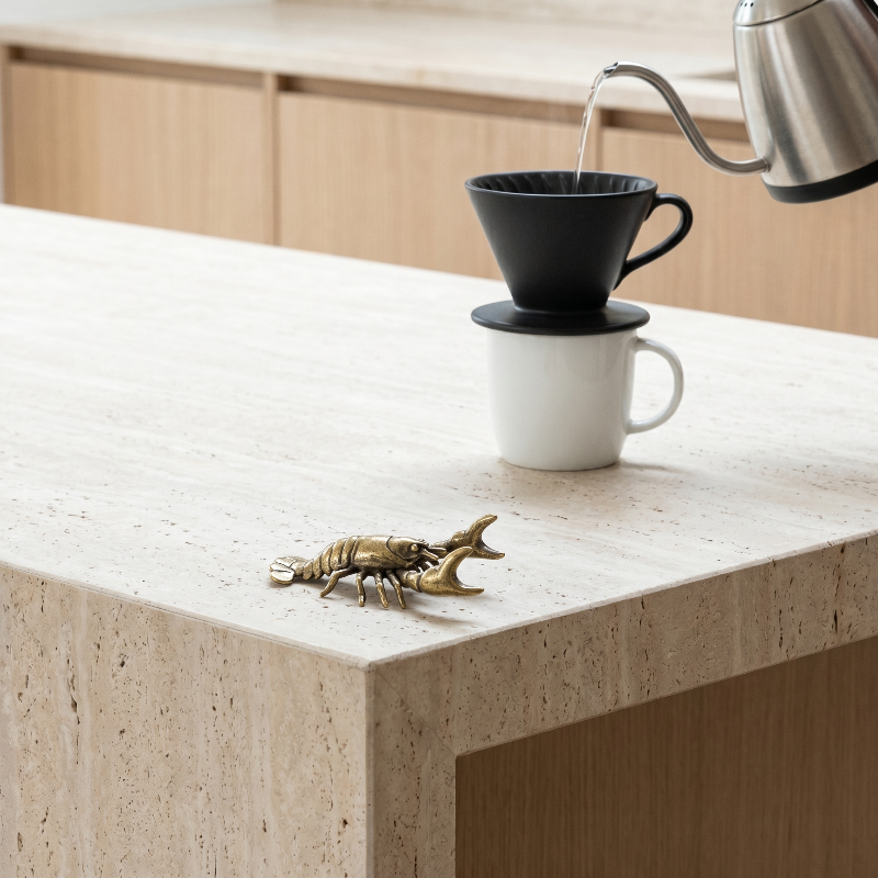 Brass crayfish figurine on kitchen counter beside coffee cup