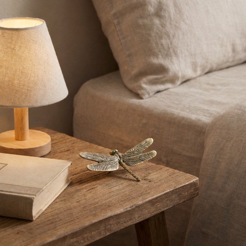 Brass dragonfly figurine on bedside table with lamp