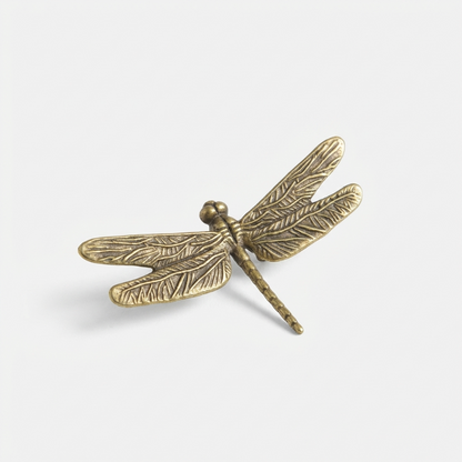 Bronze dragonfly-shaped object on a white background