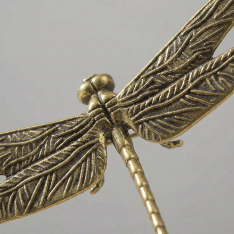 Bronze dragonfly figurine on a gray background