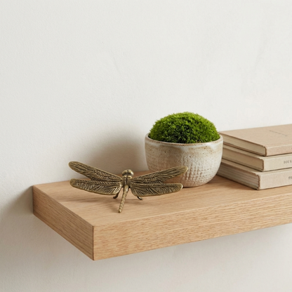 Brass dragonfly figurine on wooden tray with decorative moss
