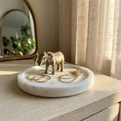 Brass elephant figurine on marble tray beside jewelry