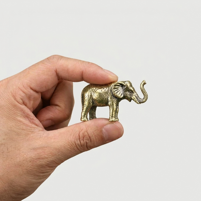 Small brass elephant figurine shown in hand for scale