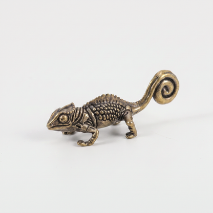 Brass chameleon figurine on an off-white background