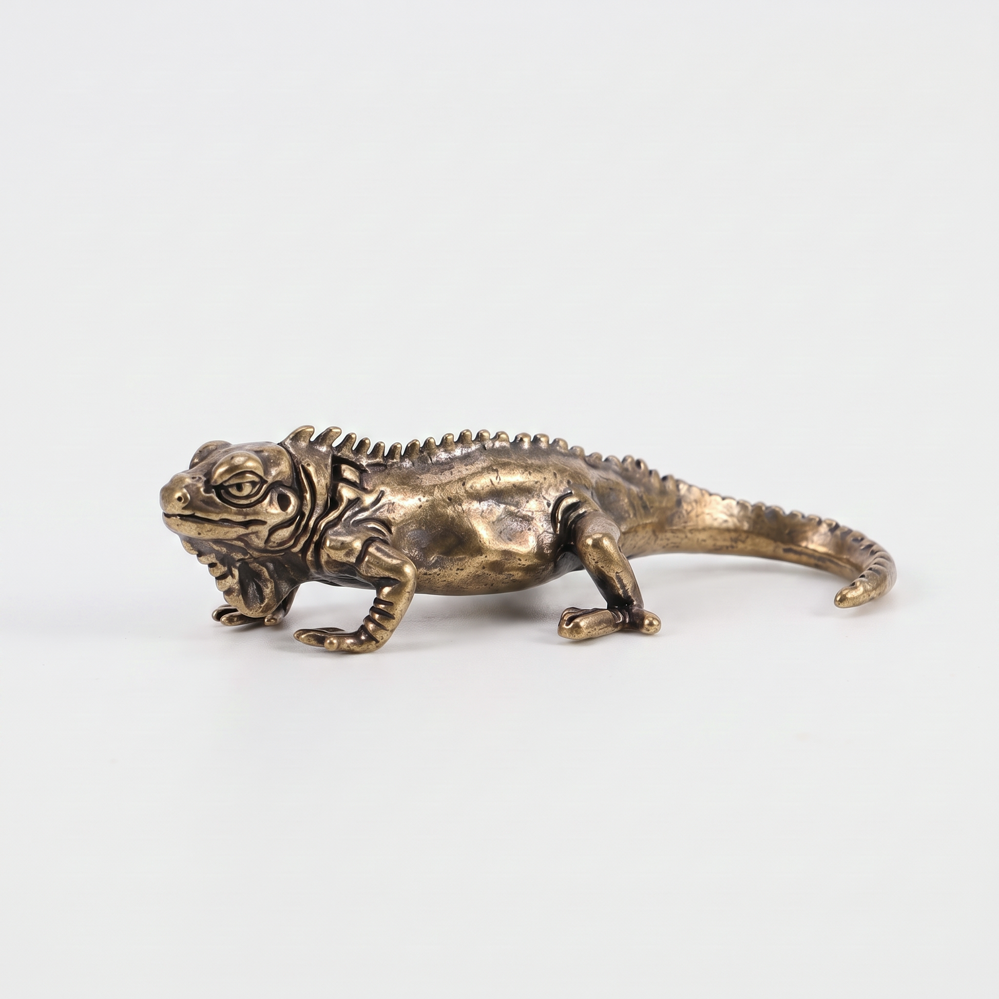 Brass iguana figurine on an off-white background