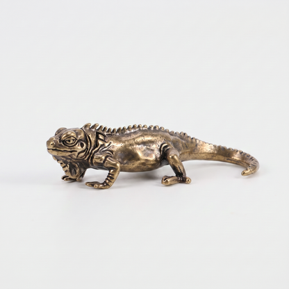 Brass iguana figurine on an off-white background