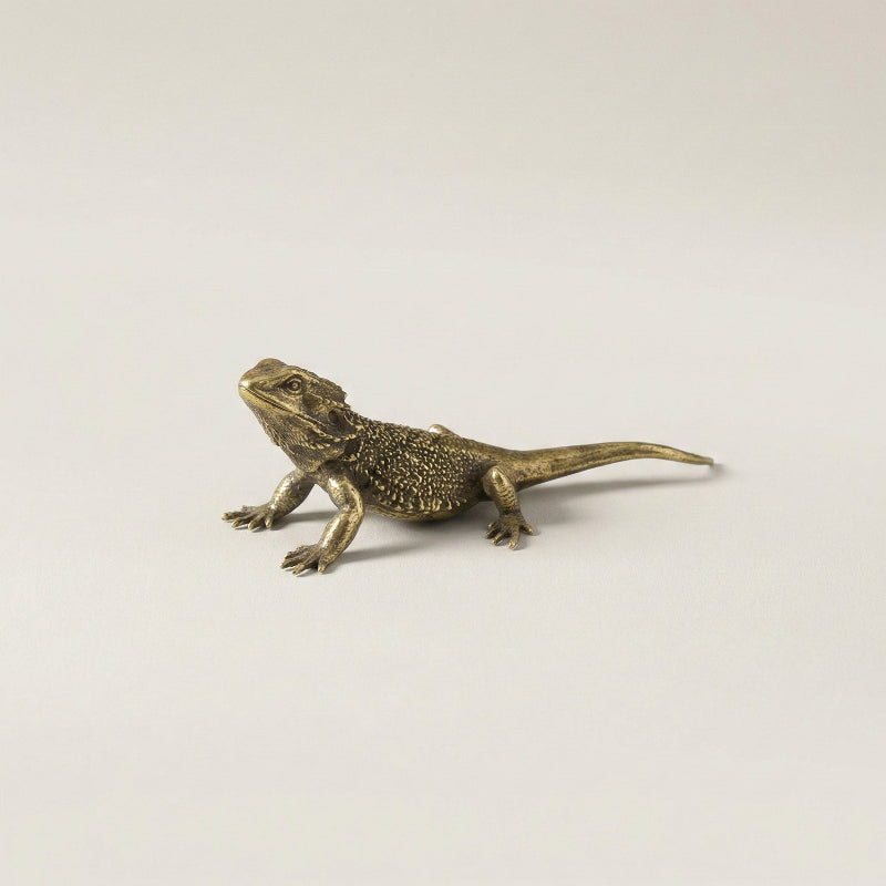 Brass lizard figurine on a light gray background