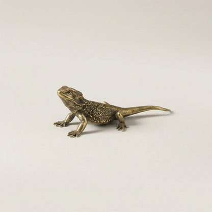 Brass lizard figurine on a light gray background