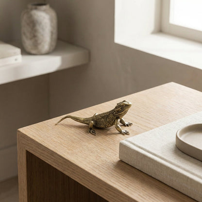 Bronze lizard sculpture on a wooden surface with a neutral background