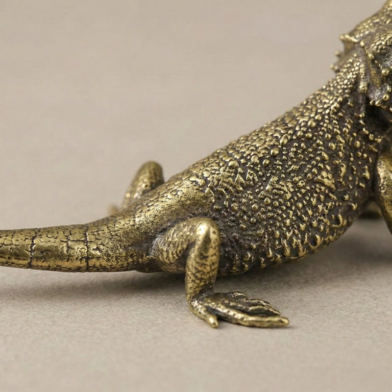 Bronze lizard figurine on a neutral background