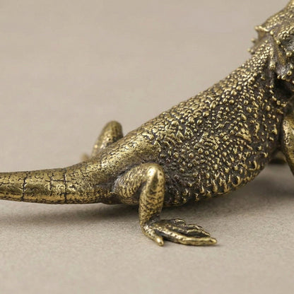 Bronze lizard figurine on a neutral background