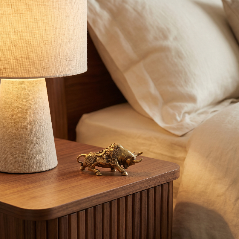 Brass lucky bullfighting figurine on bedside table beside lamp