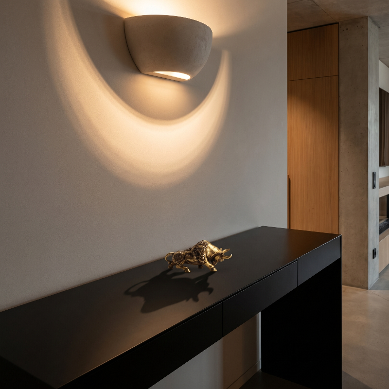 Brass lucky bullfighting figurine on black console beneath wall light