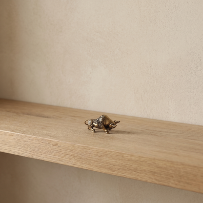 Brass lucky bullfighting figurine on floating shelf in warm natural light