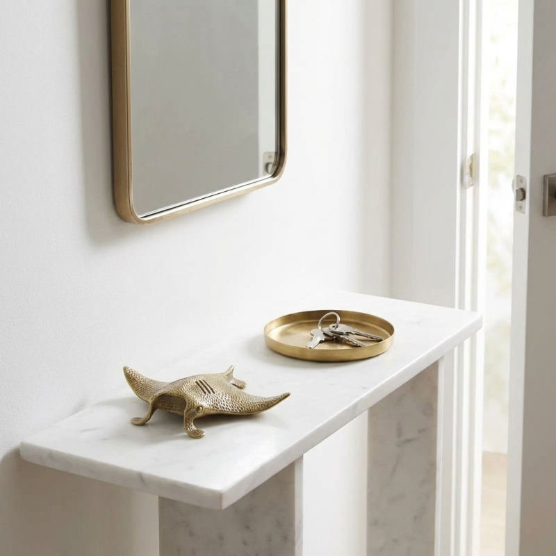 Small white table with brass manta ray styled on top.