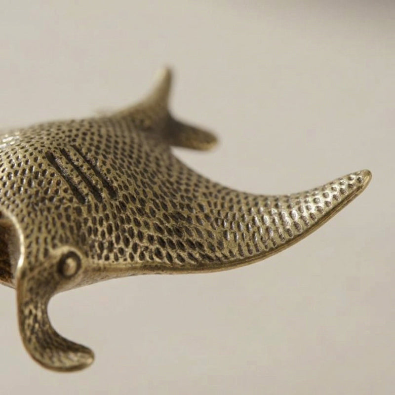 Bronze manta ray figurine on a light beige background