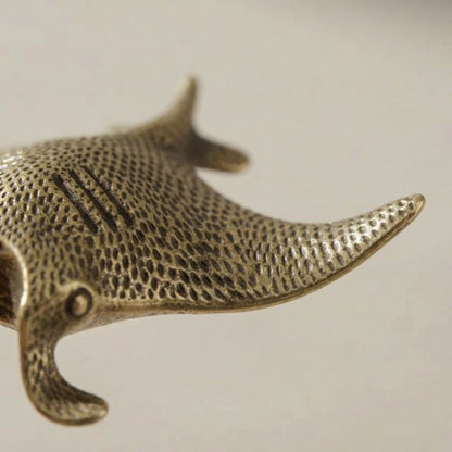 Bronze manta ray figurine on a light beige background