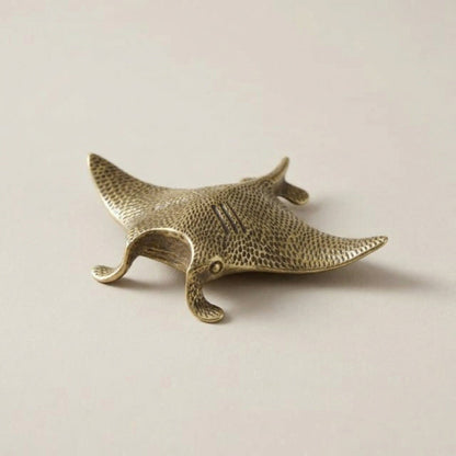 Bronze manta ray figurine on a beige background