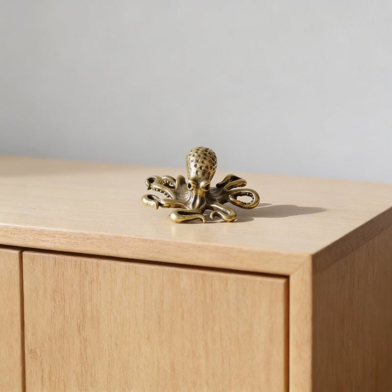 Brass octopus decorative item on a wooden surface with a neutral background