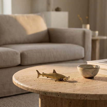 Brass hammerhead shark figurine on round coffee table in neutral living room
