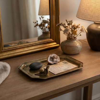 Brass snail figurine on vanity tray beside mirror and perfume