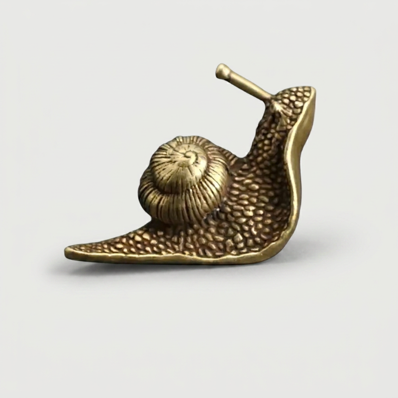 Brass snail figurine on white background facing left