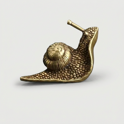 Brass snail figurine on white background facing left