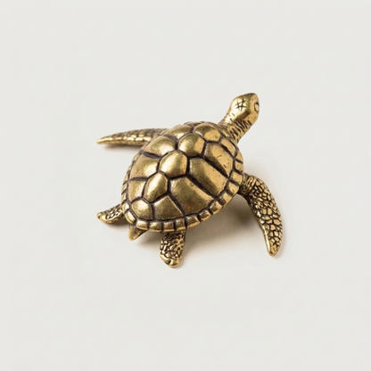Brass turtle figurine on white background facing left
