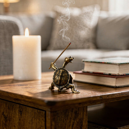 Tortoise-shaped incense burner with a lit candle and books on a wooden surface.