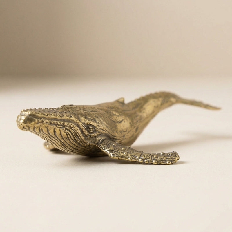 Bronze whale figurine on a beige background