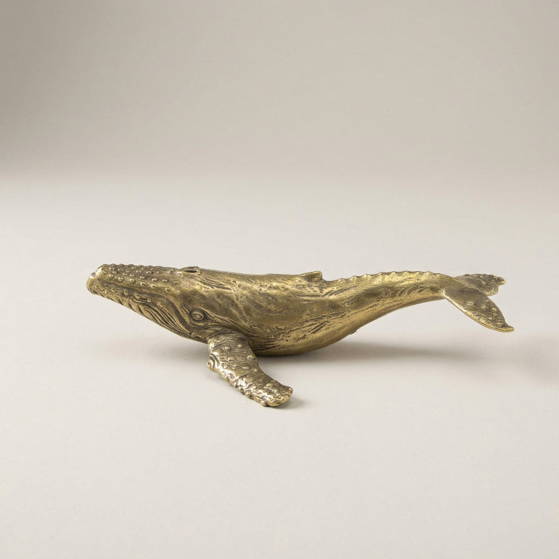 Bronze whale sculpture on a light gray background