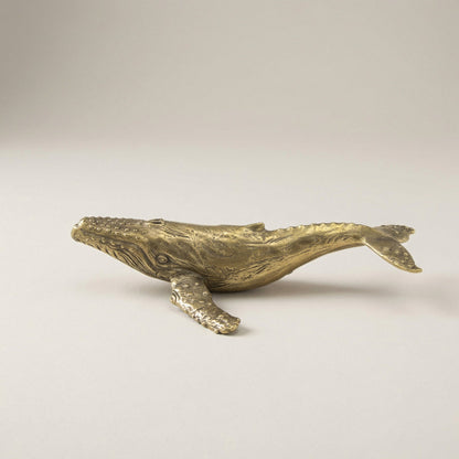 Bronze whale sculpture on a light gray background