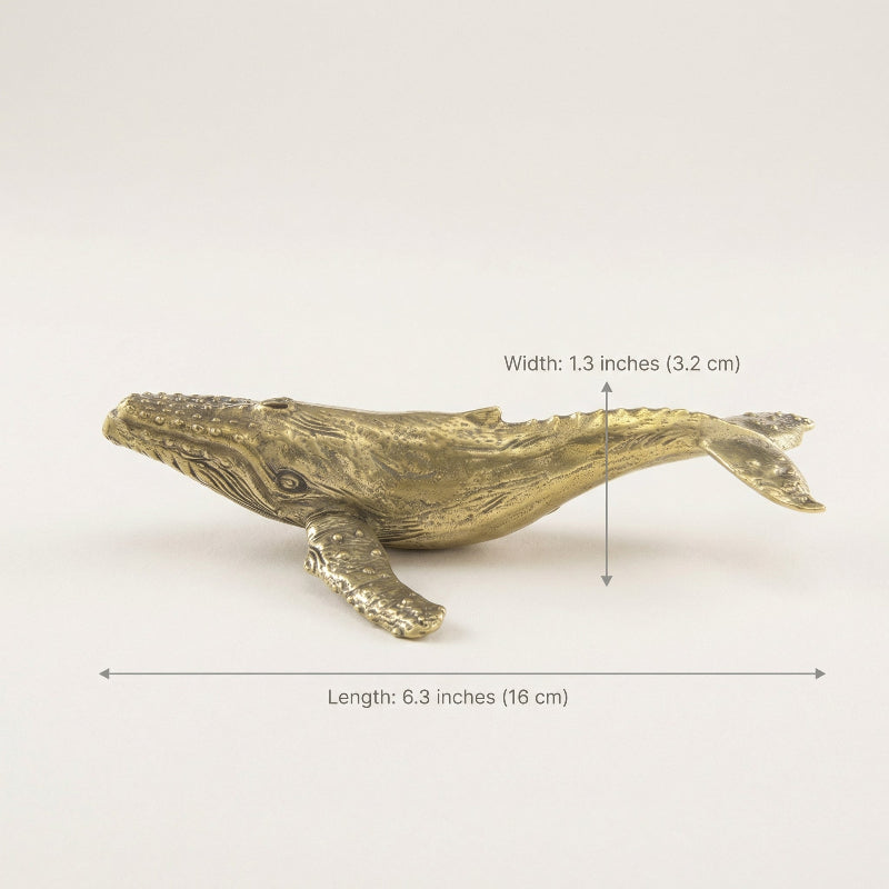 Brass whale-shaped object with measurements on a white background