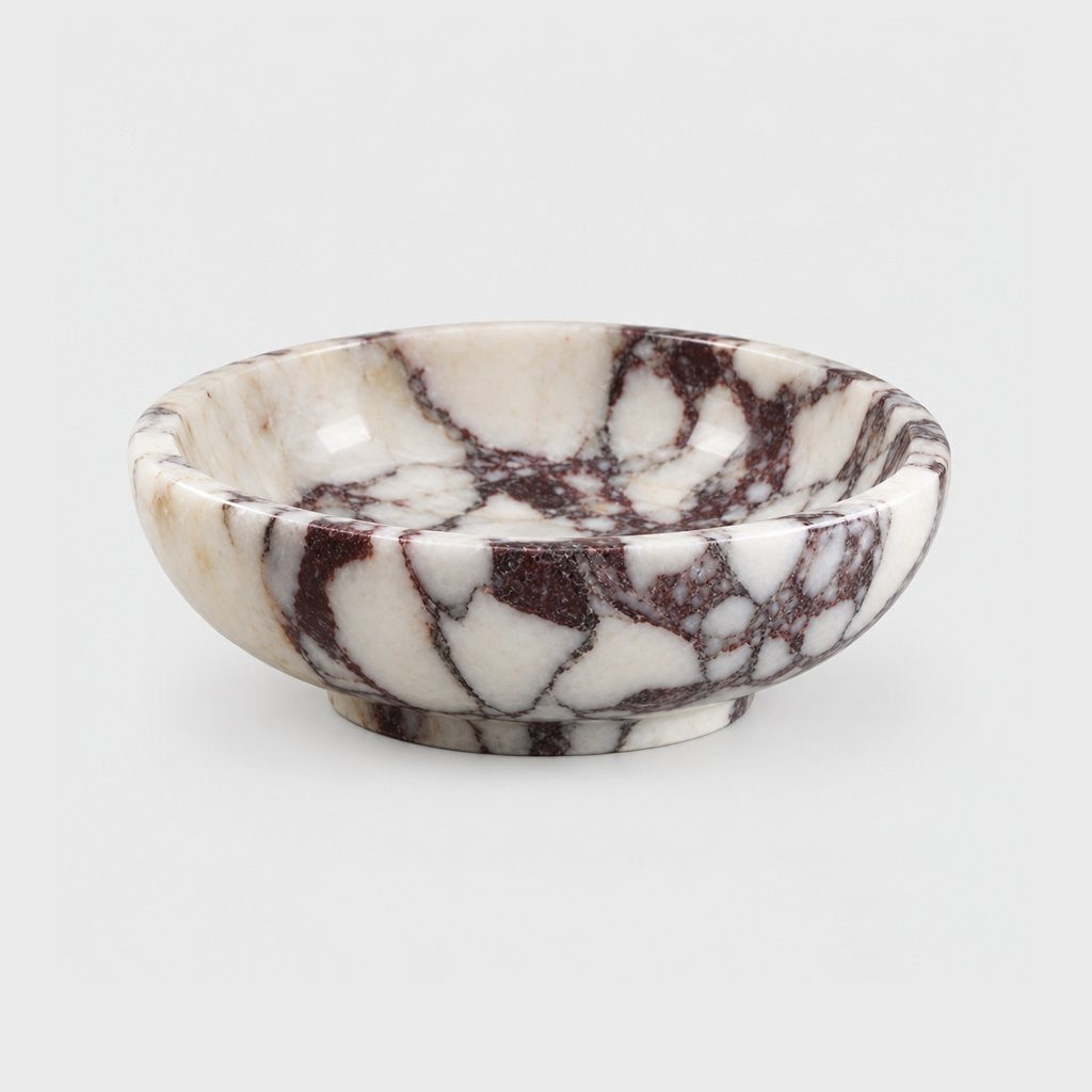 Empty shallow white marble bowl with burgundy veining and a low footed base, on a plain light gray background