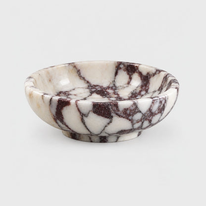 Empty shallow white marble bowl with burgundy veining and a low footed base, on a plain light gray background