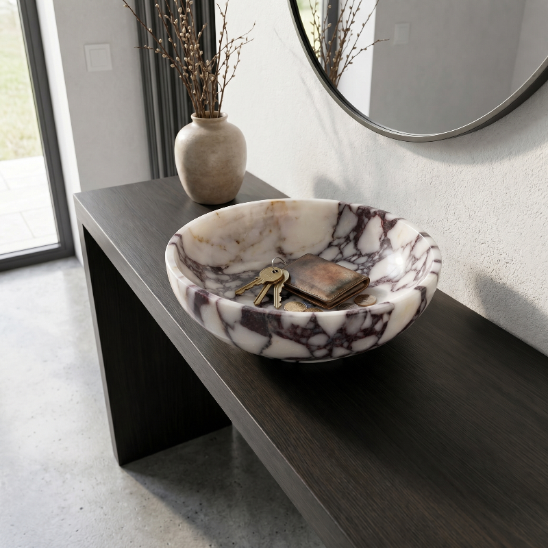 Marble-patterned bowl with keys on a dark wooden surface, with a vase and mirror in the background.