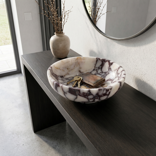 Marble-patterned bowl with keys on a dark wooden surface, with a vase and mirror in the background.