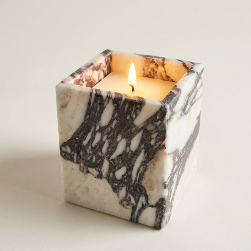 Marble-patterned candle holder with a lit candle on a light background