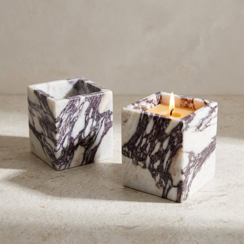 Marble-patterned candle holder with a lit candle on a neutral background