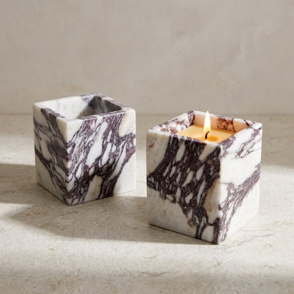 Marble-patterned candle holder with a lit candle on a neutral background