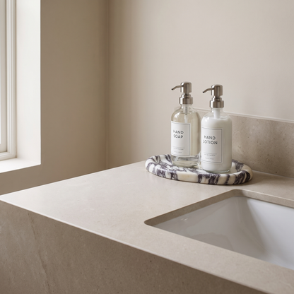 Calacatta marble tray on a bathroom vanity holding amber skincare bottles, Kiyo Home