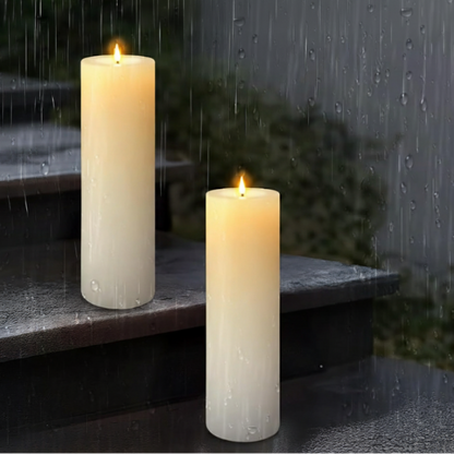 Two waterproof LED pillar candles with glowing faux flames sit on wet stone steps during a rainy night.