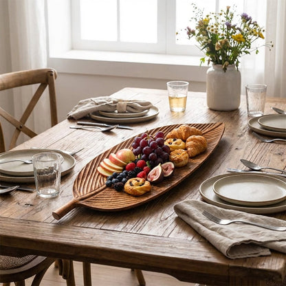 Carved Wood Leaf Serving Tray filled with fresh fruit and pastries on a set dining table