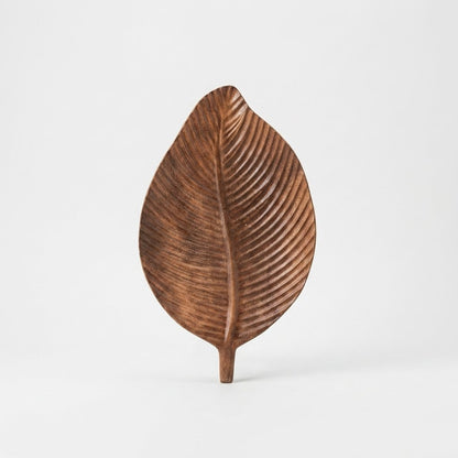 Dark wood Carved Leaf Serving Tray standing upright, hero shot on a clean off-white background