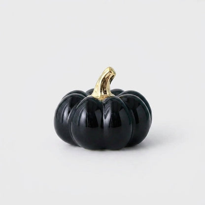 Black ceramic pumpkin with a gold stem on a white background