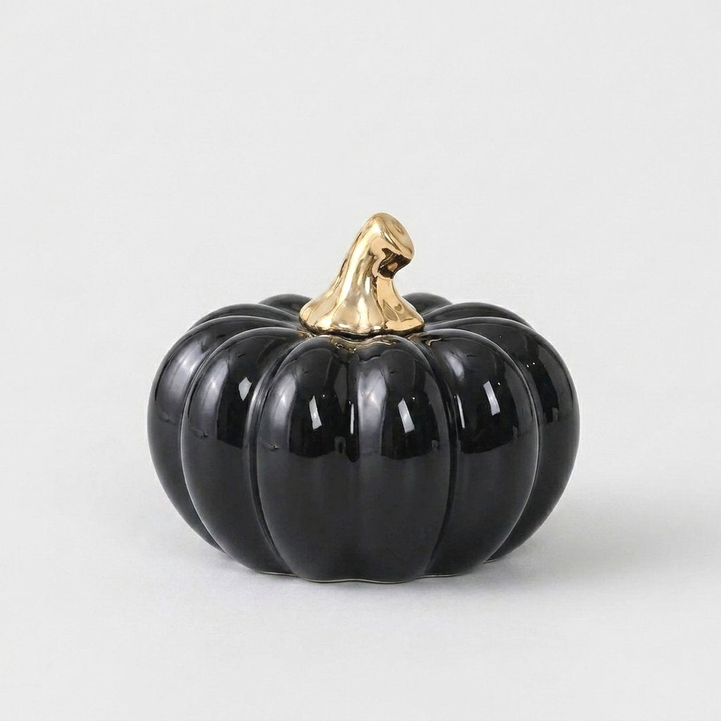 Black ceramic pumpkin with a gold stem on a white background, alternate angle
