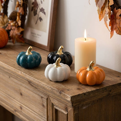Blue, black, white, and orange small ceramic pumpkins on a mantel with a picture frame and lit candle