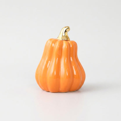 Orange ceramic gourd with a gold stem on a white background