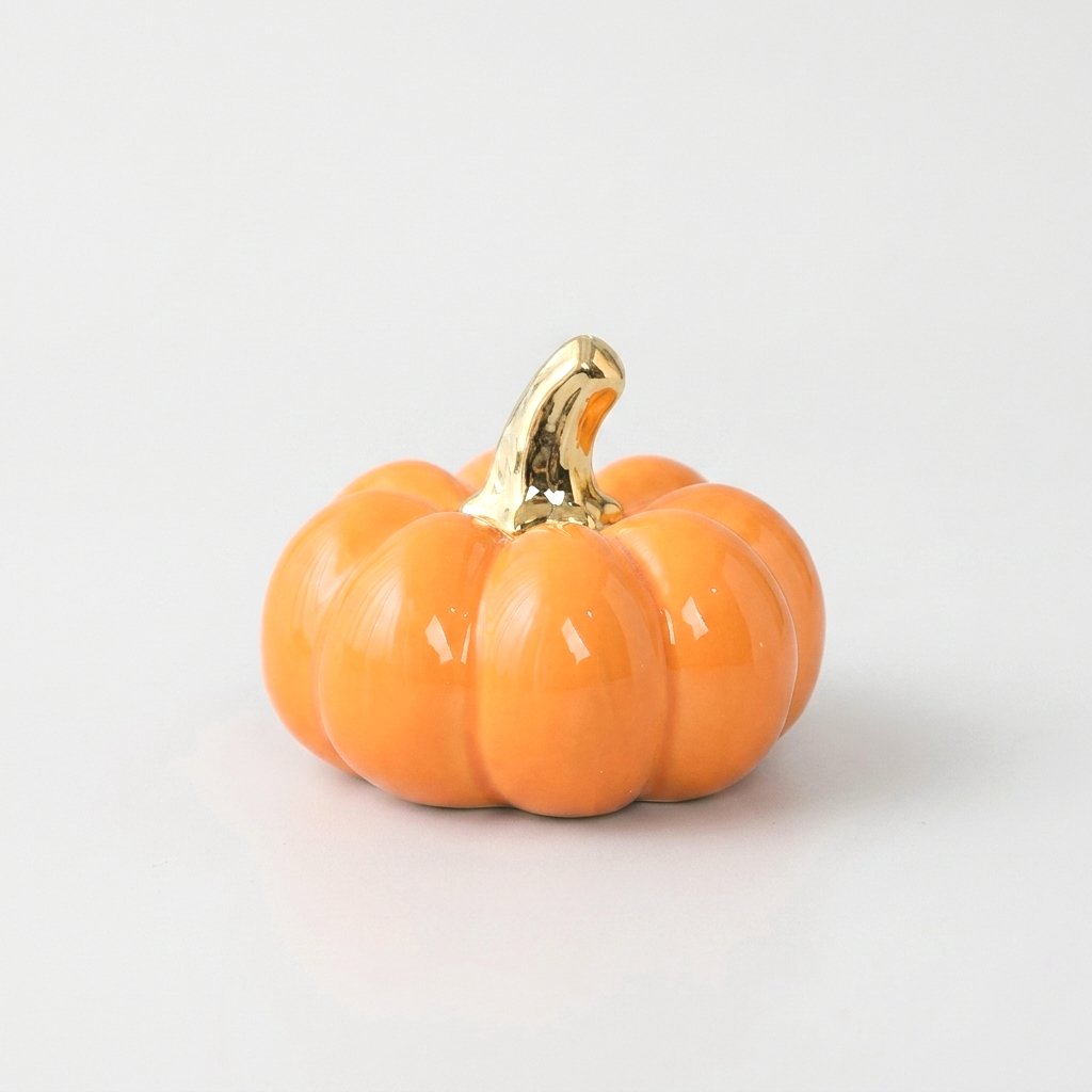 Orange ceramic pumpkin with a gold stem on a white background