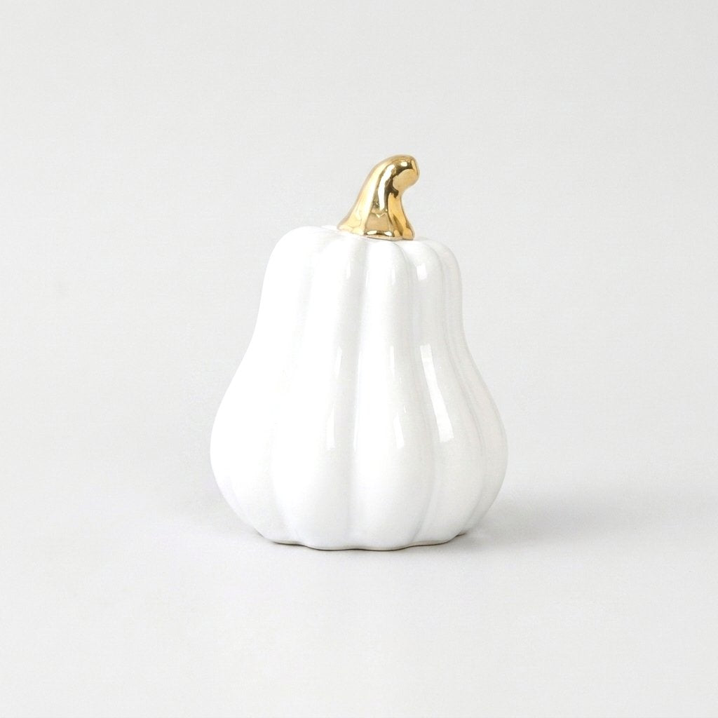 White ceramic gourd with a gold stem on a white background